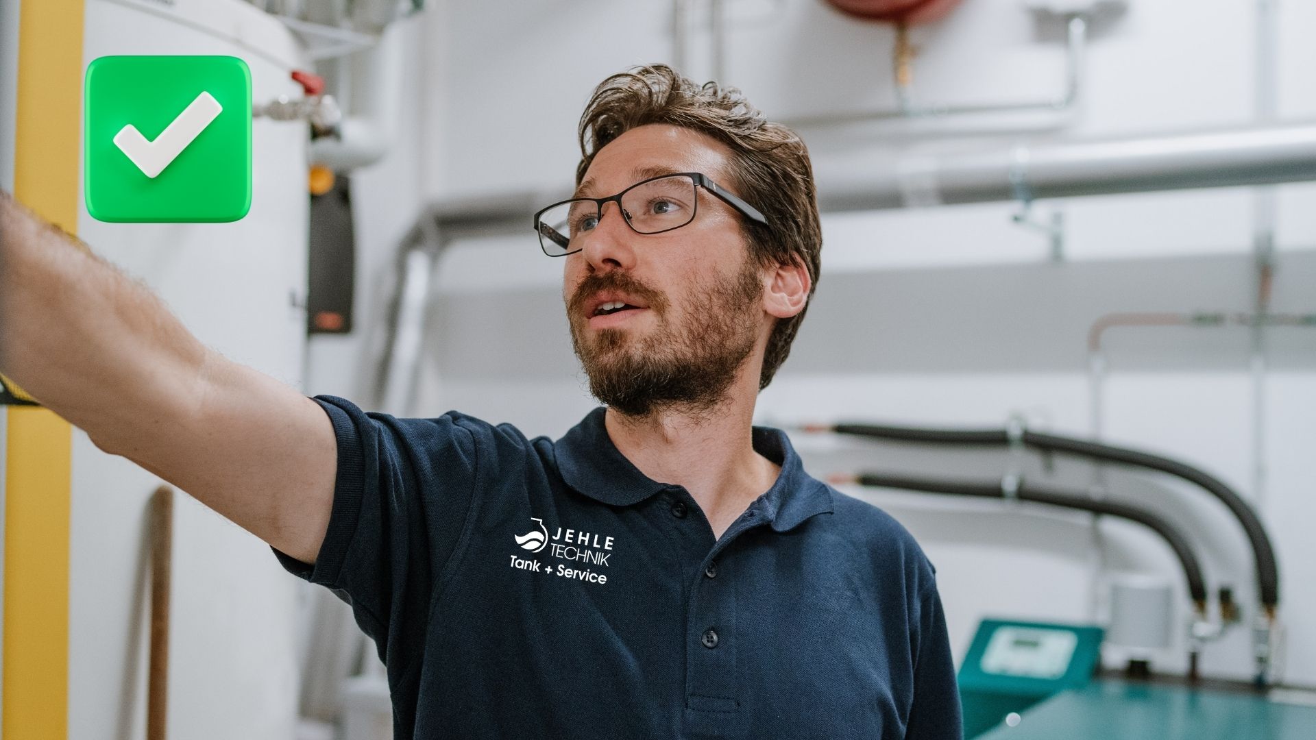 Mann mit Brille, zeigt auf etwas, trägt ein dunkelblaues Polohemd, im technischen Raum.