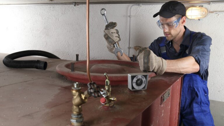 Fachmann im Blaumann öffnet Heizöltank