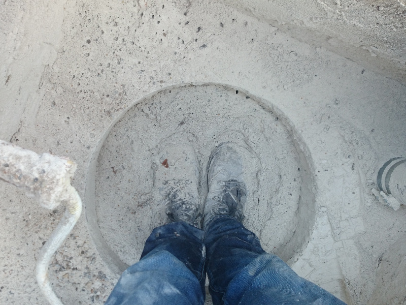 Eine Person mit staubigen Schuhen steht in einer runden Vertiefung aus hellem Beton