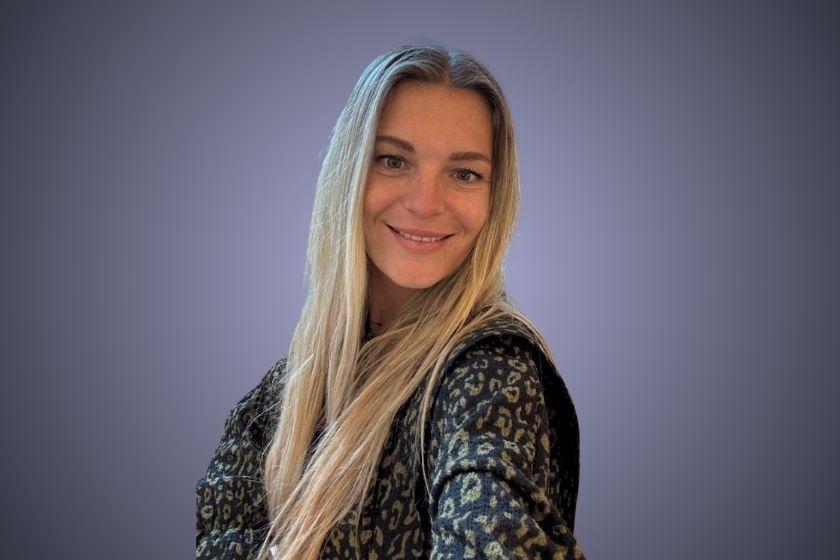 Eine Frau mit langem blondem Haar und lässigem Leo-Muster-Pullover vor violettem Hintergrund