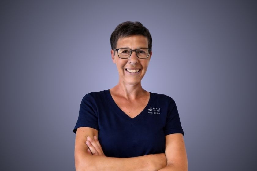 Kurzhaarige Person mit neutralem Blick im blauen Shirt und verschleiertem Gesicht